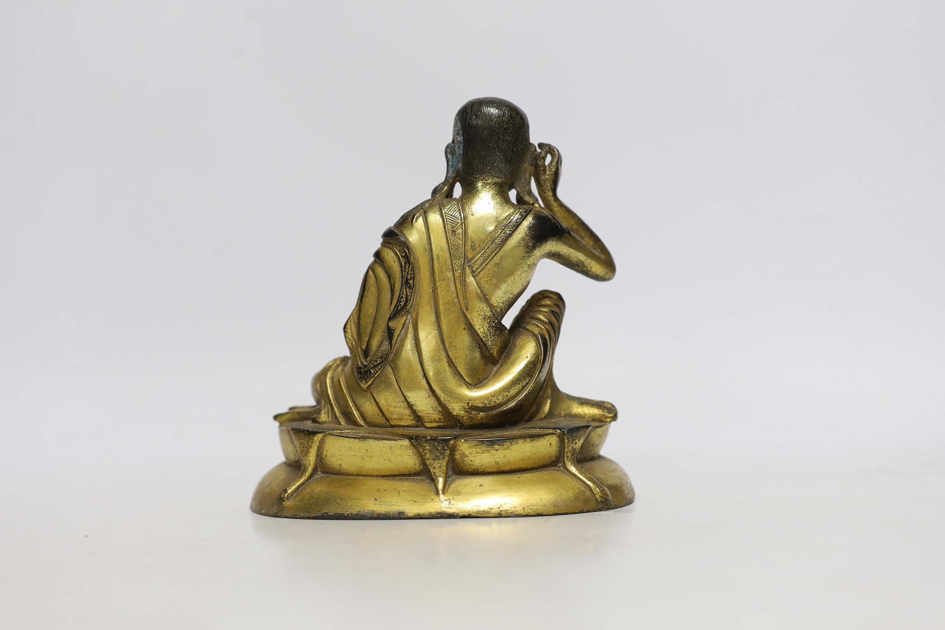 A Sino-Tibetan gilt bronze seated figure of Milarepa, 14cm high